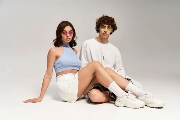 Casal jovem mostra moda enquanto abraçam um ao outro em um ambiente acolhedor estúdio — Fotografia de Stock
