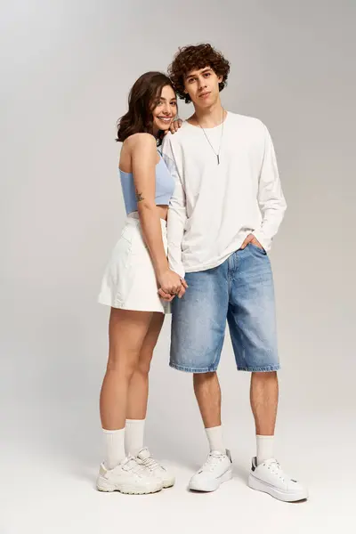 Ein junges Paar hält Händchen und strahlt vor minimalistischem Hintergrund Liebe und Stil aus. — Stockfoto