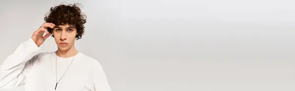 Очаровательный стильный мужчина с вьющимися волосами в модном наряде на спокойном белом фоне. — стоковое фото