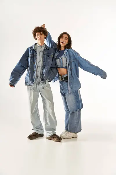 A young couple poses playfully in trendy denim outfits in a bright studio. — Stock Photo