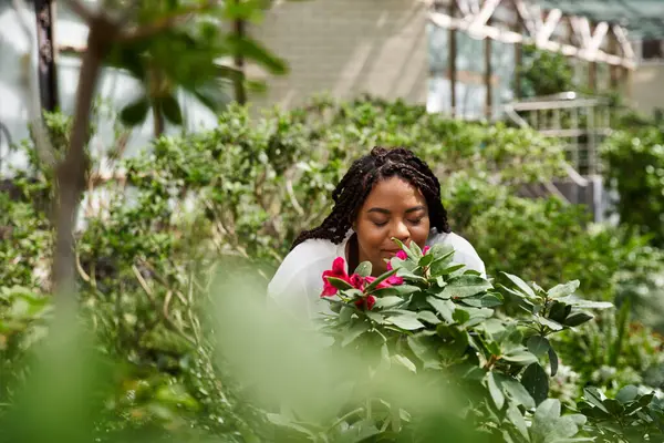 Women engages with blossoming plants in a lush greenhouse, embracing natures beauty. — Stock Photo