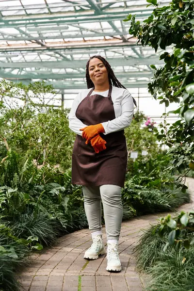 A confident African American woman with braids nurtures plants in a greenhouse. — Stock Photo