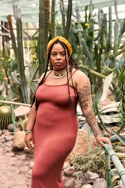 A graceful African American woman with braids shines among tropical plants. — Stock Photo