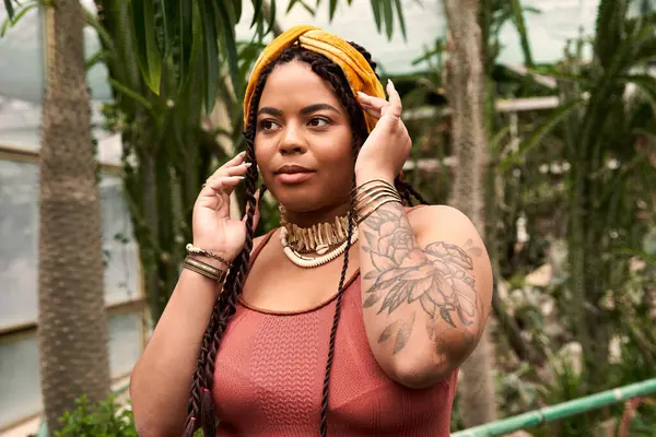 Uma mulher afro-americana bonita com tranças desfruta de um momento cercado por plantas diversas. — Fotografia de Stock