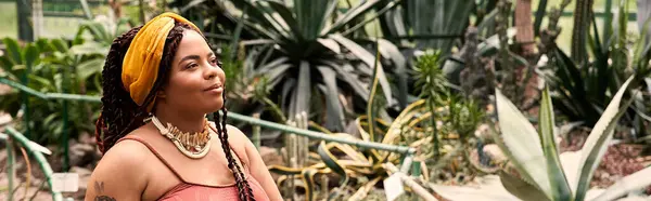 A pretty African American woman enjoys the vibrant plants in a serene greenhouse setting, banner — Stock Photo