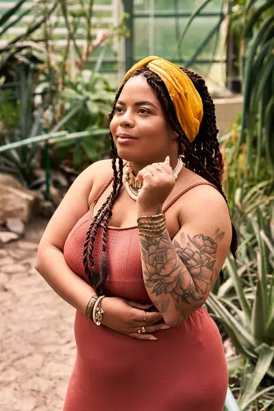 A blissful african american woman with braids enjoys the serene atmosphere in a greenhouse. — Stock Photo