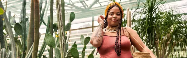 A charming African American woman with braids relaxes in a lush greenhouse, banner — Stock Photo