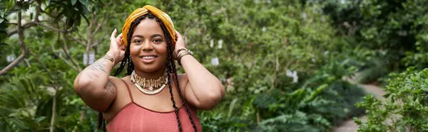 A radiant woman with braids showcases her joy while surrounded by thriving plants, banner — Stock Photo