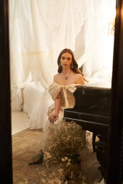 A beautiful young woman in a vintage dress is poised by a piano, exuding timeless elegance. — Stock Photo