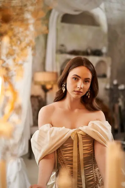A beautiful young woman poses gracefully, surrounded by candlelight in a vintage setting. — Stock Photo