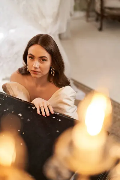A beautiful young woman in an elegant dress gazes thoughtfully amidst a warm, vintage setting. — Stock Photo