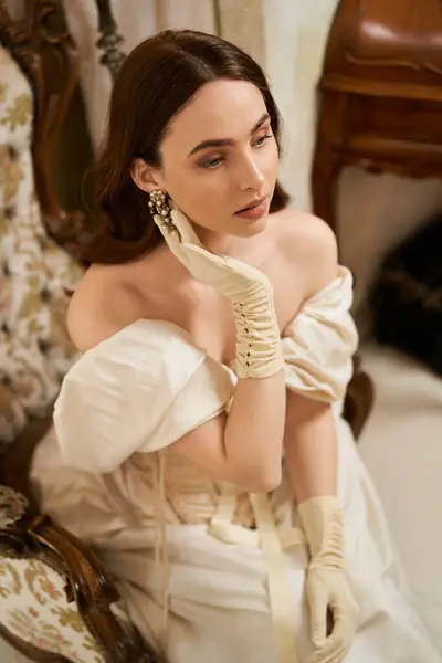 Una hermosa joven adornada con atuendo vintage, irradiando elegancia en un ambiente atemporal. - foto de stock