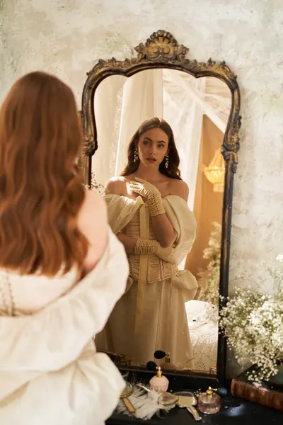 Una donna graziosa guarda il suo riflesso, vestita con uno splendido abito vintage. — Foto stock
