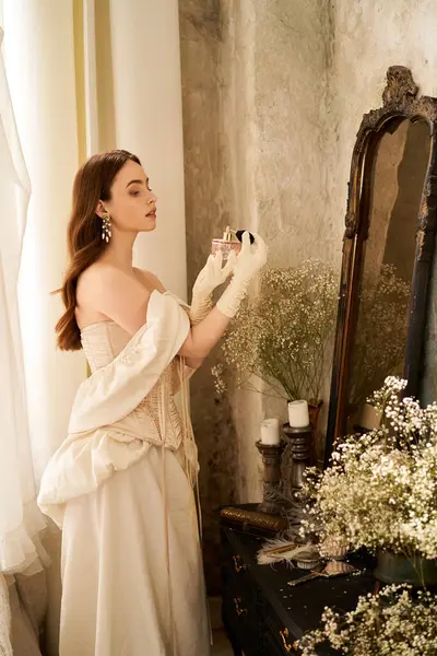 Una donna graziosa in un abito vintage riflette da uno specchio ornato di fiori. — Foto stock