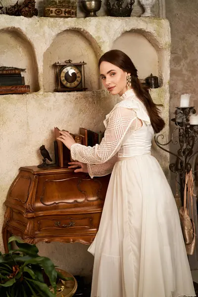 Una joven elegante arregla delicadamente los libros en un escritorio antiguo, exudando encanto vintage. - foto de stock