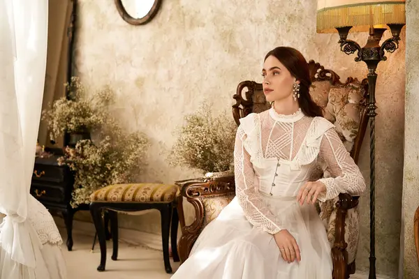 A young woman in a vintage dress sits gracefully among decor, showcasing elegance and charm. — Stock Photo