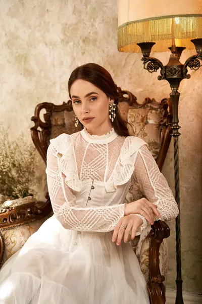 A young woman in a vintage gown sits gracefully in an ornate chair, exuding elegance. — Stock Photo