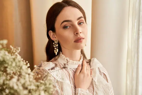 A young woman with an elegant vintage look poses gracefully by soft drapes and flowers. — Stock Photo