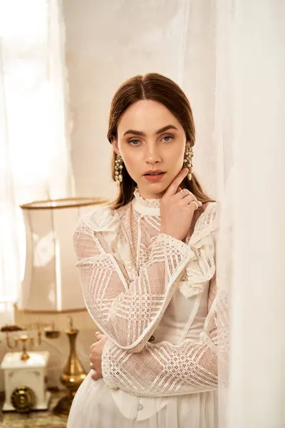 A beautiful woman in a vintage dress showcases classic elegance in a cozy, softly lit space. — Stock Photo