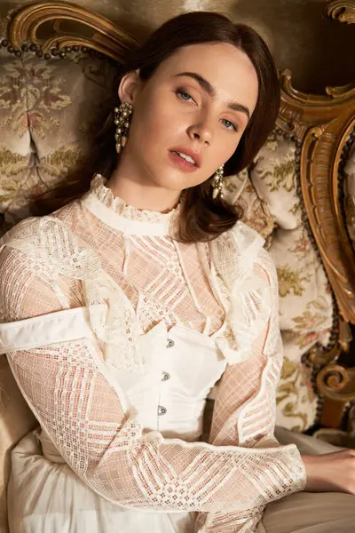 A young woman in a vintage dress poses gracefully, exuding elegance and charm in her setting. — Stock Photo