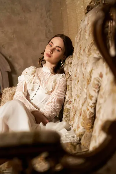 A beautiful young woman relaxes on an ornate couch, showcasing vintage elegance and charm. — Stock Photo