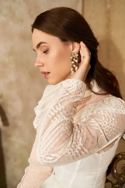 The beautiful woman delicately adjusts her earring, exuding vintage charm and elegance. — Stock Photo