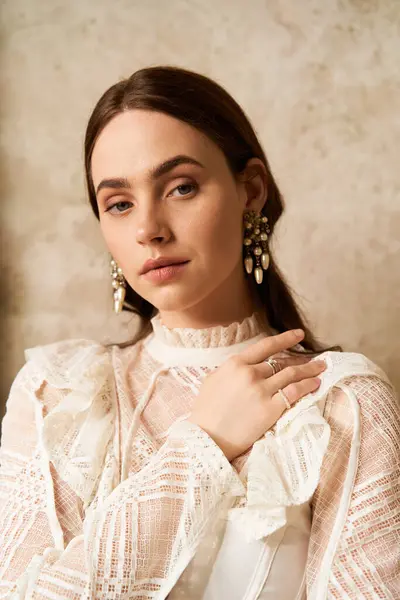 A beautiful young woman showcases her vintage dress and elegant earrings in a serene setting. — Stock Photo
