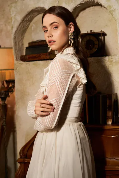 Una giovane donna in un bellissimo abito vintage mette in mostra l'eleganza in uno spazio interno accogliente e rustico. — Foto stock