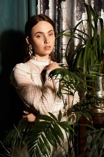 Una hermosa joven posa graciosamente en un vestido vintage en medio de una vibrante vegetación. - foto de stock