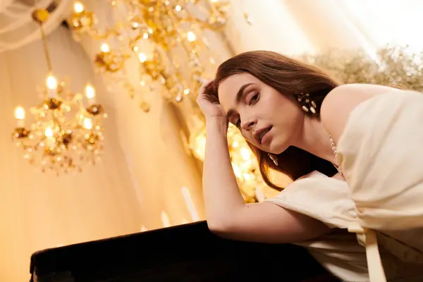 A beautiful young woman relaxes in an elegant vintage dress surrounded by golden chandeliers. — Stock Photo