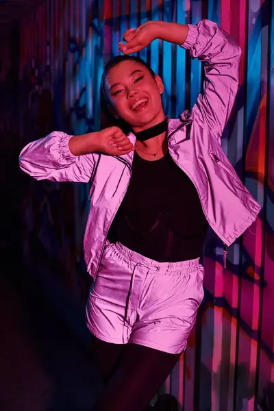 Young woman poses playfully in a colorful urban backdrop, showcasing her fashion flair. — Stock Photo