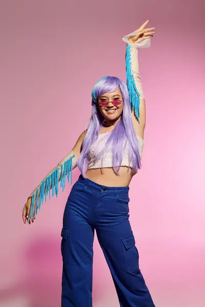 A stylish woman confidently poses against a pink backdrop, showcasing her unique look. — Stock Photo
