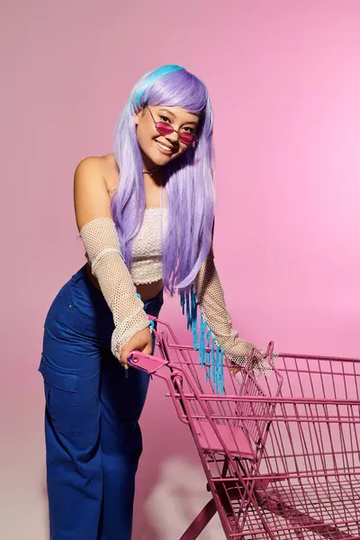 Stylish woman showcases her unique fashion sense while smiling beside a bright shopping cart. — Stock Photo