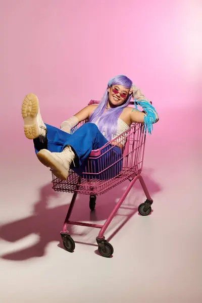 A woman with long pastel hair relaxes in a pink cart, flaunting her unique style. — Stock Photo
