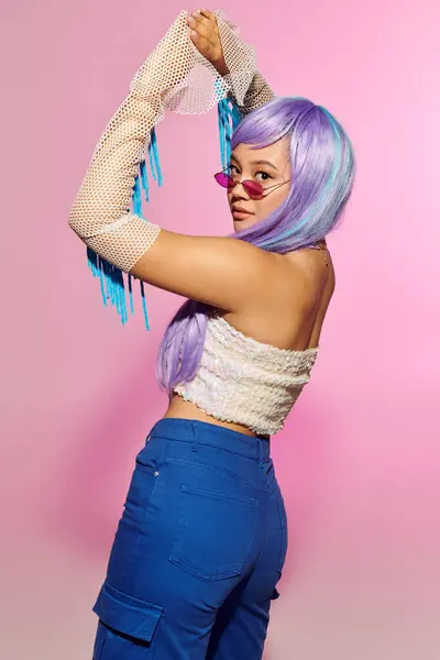 Mujer pelo de colores brillantes muestra su traje de moda mientras disfruta de un momento divertido en el interior. - foto de stock