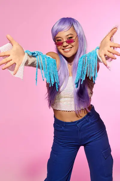 A trendy woman in colorful attire poses joyfully, radiating confidence against a pink backdrop. — Stock Photo