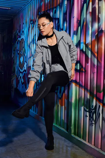 A confident woman showcases her fashion in an urban setting rich with colorful art. — Stock Photo
