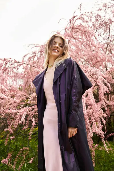 Mujer rubia sonríe en vestido de primavera por el árbol en flor. - foto de stock