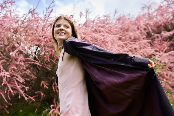 Donna sorridente in abito gode di calda giornata floreale. — Foto stock