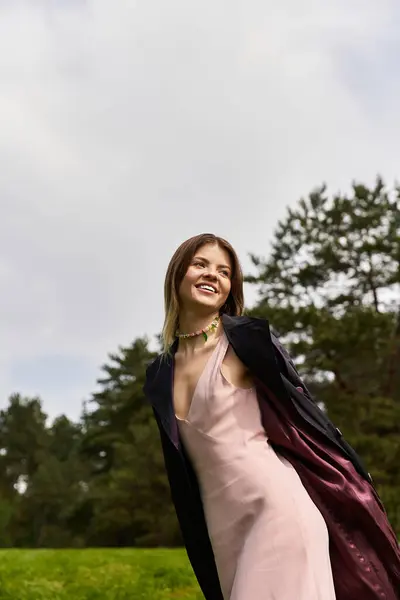 Smiling woman in pale dress walks through green field, carefree. — Stock Photo