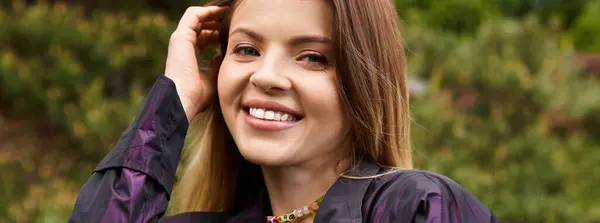 Mujer joven sonríe, mano cerca del cabello, naturalmente seductora. - foto de stock