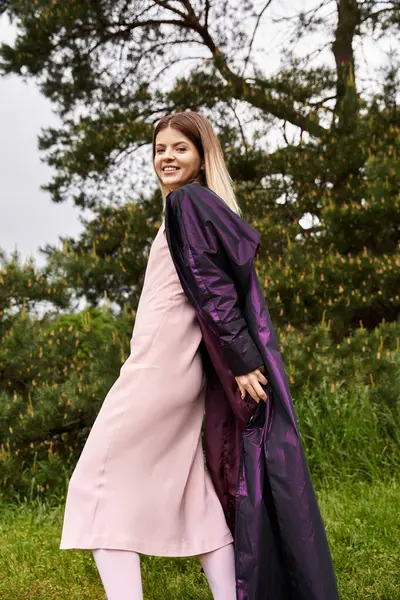 Pink dress, purple coat, smiling woman outdoors. — Stock Photo