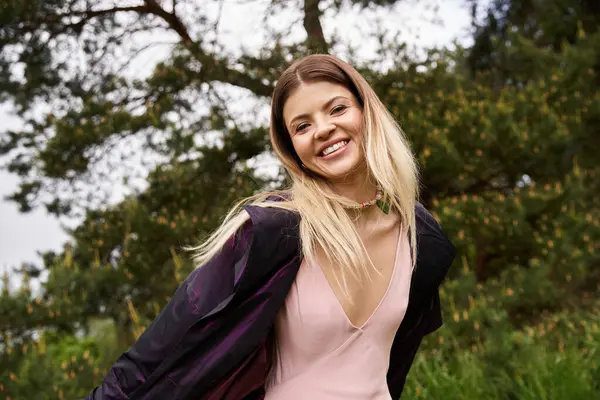 Eine junge Frau mit blonden Haaren lächelt breit im Wald. — Stockfoto