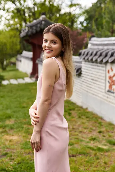 Pink dress on fashionable woman, smiling in asian garden. — Stock Photo