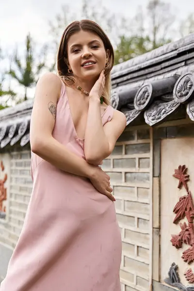 Pink dress, smiling woman by Korean wall in garden. — Stock Photo