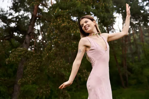 A young woman in a light dress dances in a forest. — Stock Photo