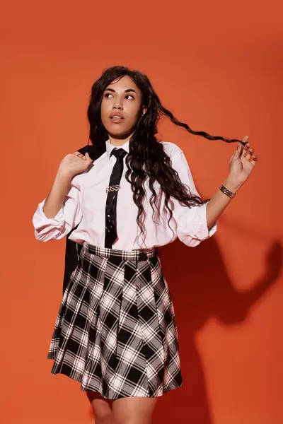 A confident young woman poses stylishly against an orange wall, embodying student fashion. — Stock Photo