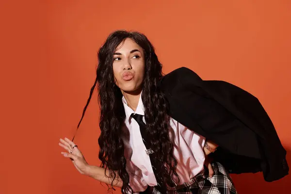 Mujer joven muestra moda única y confianza contra una pared naranja audaz, irradiando energía. - foto de stock
