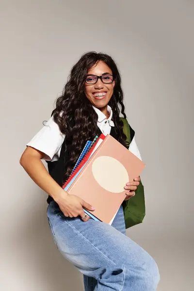 Confident young woman in bright attire holds colorful books in a casual setting. — Stock Photo