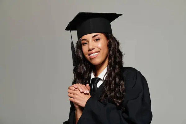 Hermosa mujer joven en traje de graduación se prepara alegremente para el próximo capítulo de su vida. - foto de stock
